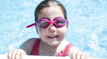 Bambina che fa sport in piscina (nuota)
